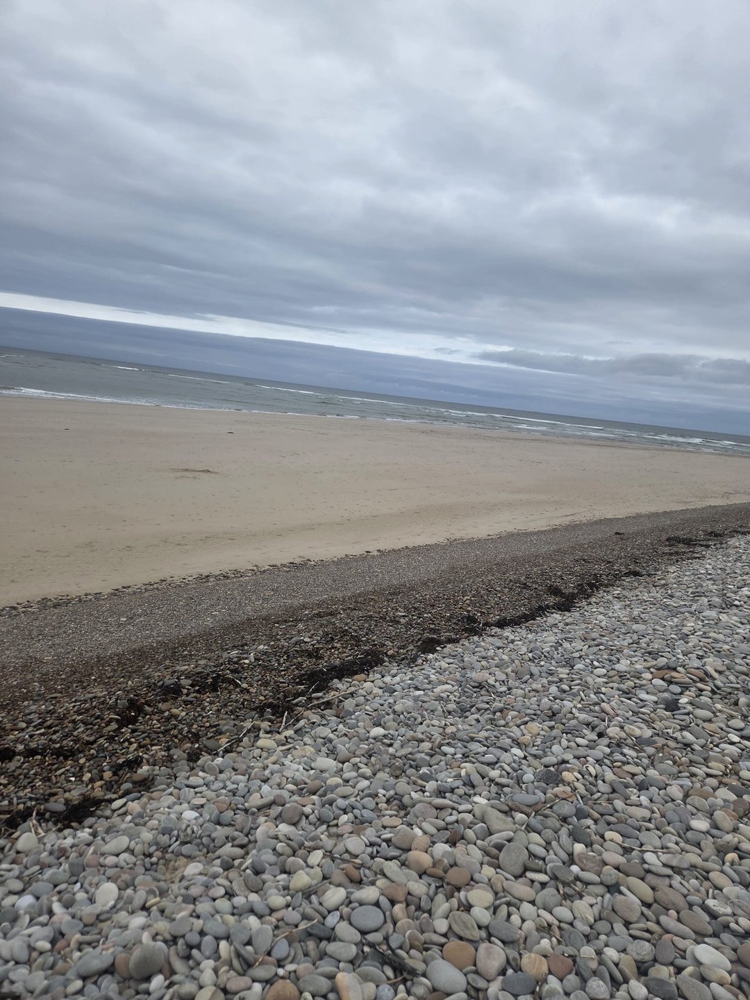 Findhorn beach under a grey sky, pebbles in the foreground