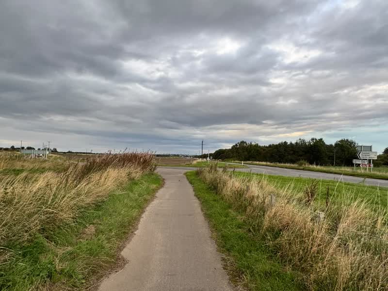 A tarmac path beside a country road, with a signpost for Hopeman and Burghead