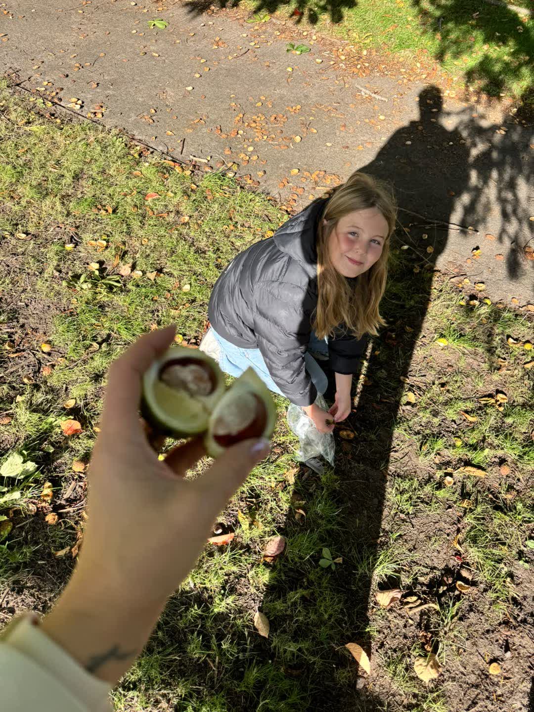 One of Gillian's girls crouched on the grass collecting conkers on an autumn walk