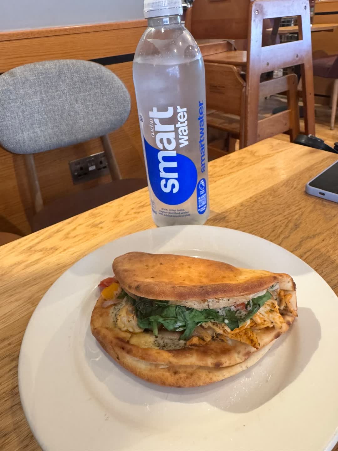 A chicken and salad flatbread on a plate with a bottle of water