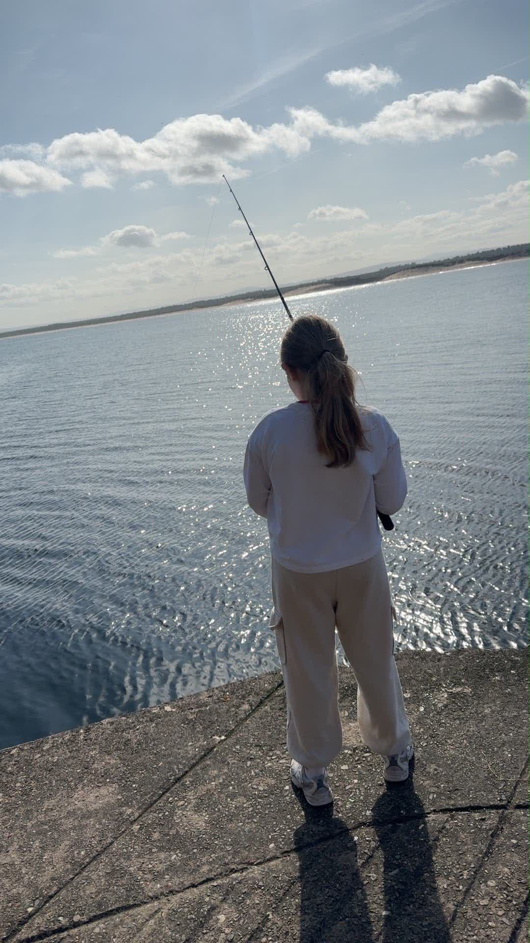 One of Gillian's girls fishing from the harbour wall, looking out over the water
