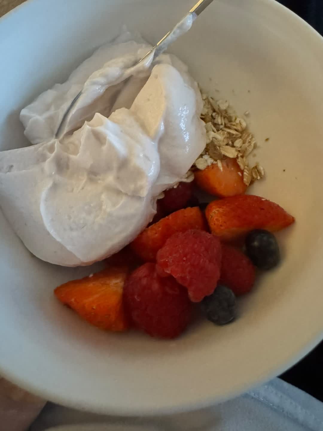 A bowl of yogurt with oats, strawberries, raspberries and blueberries