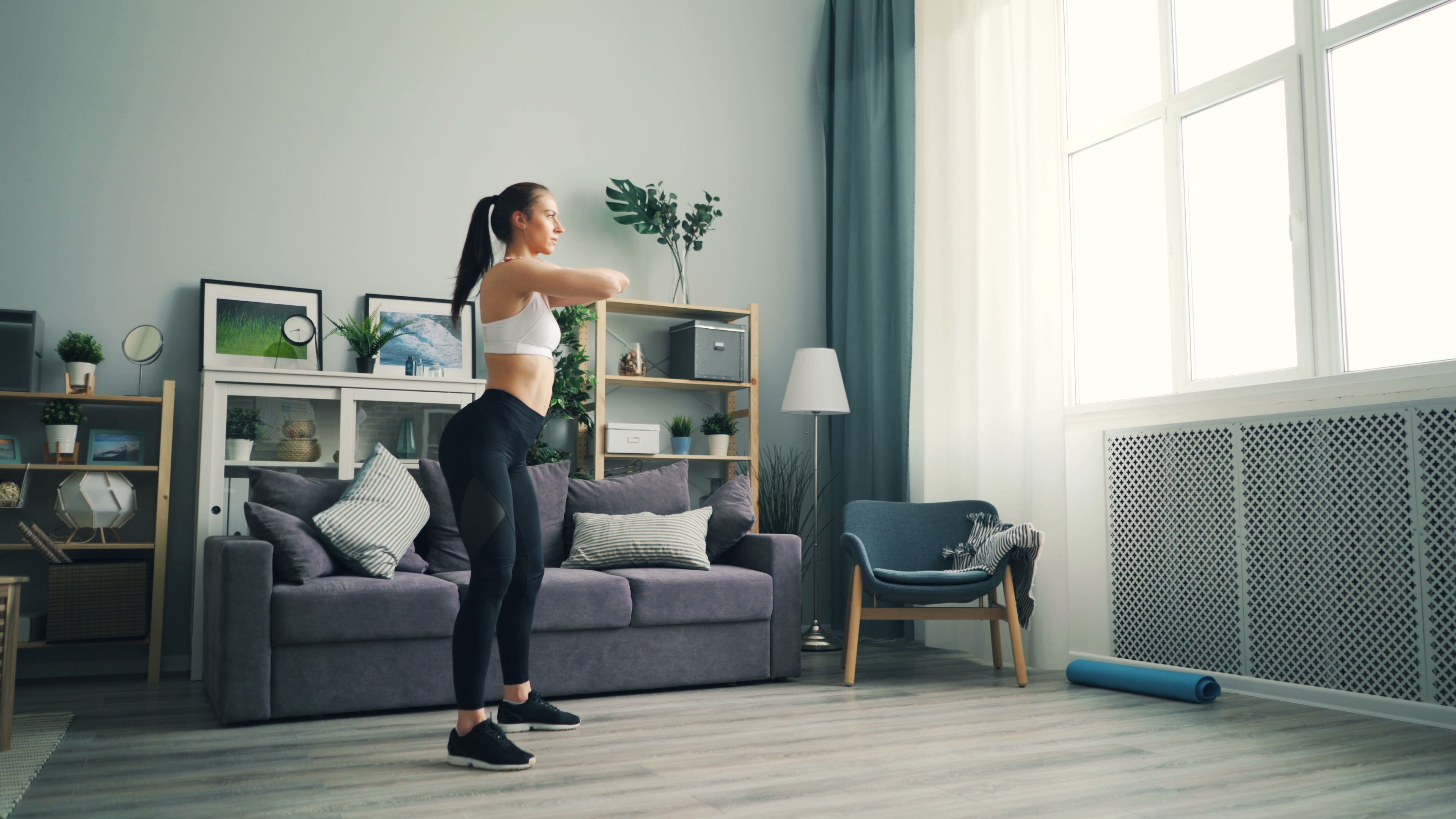 A woman doing bodyweight squats at home in her living room