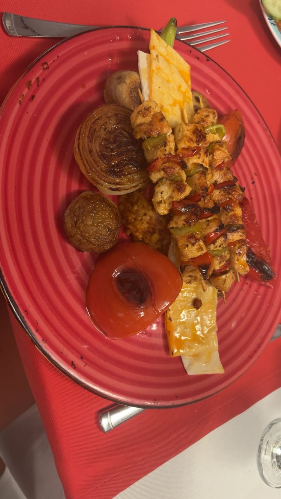 A plate of chicken skewers with grilled onion, tomato and peppers