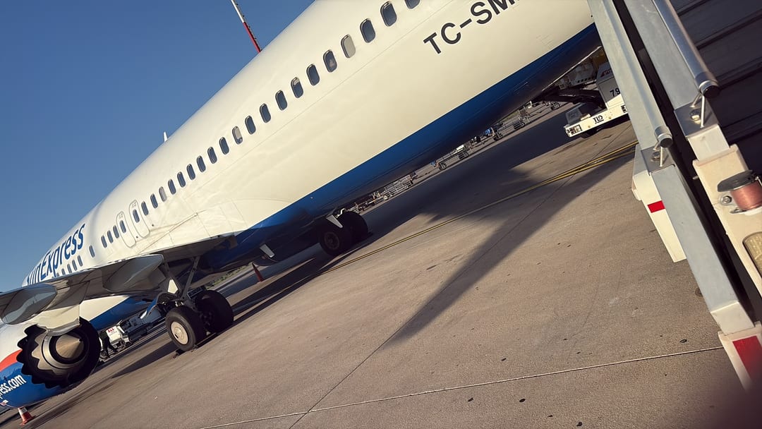 A SunExpress aircraft on the tarmac under a clear blue sky
